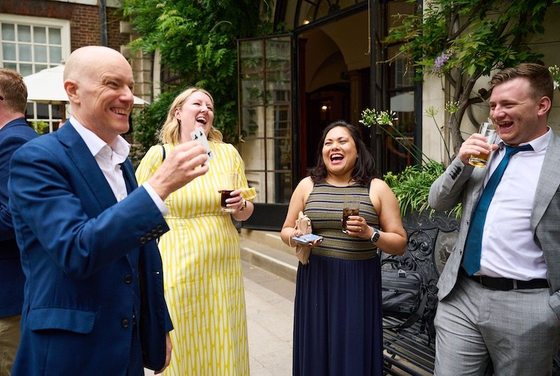 Darren Delaney performing magic and guests laughing at a garden party