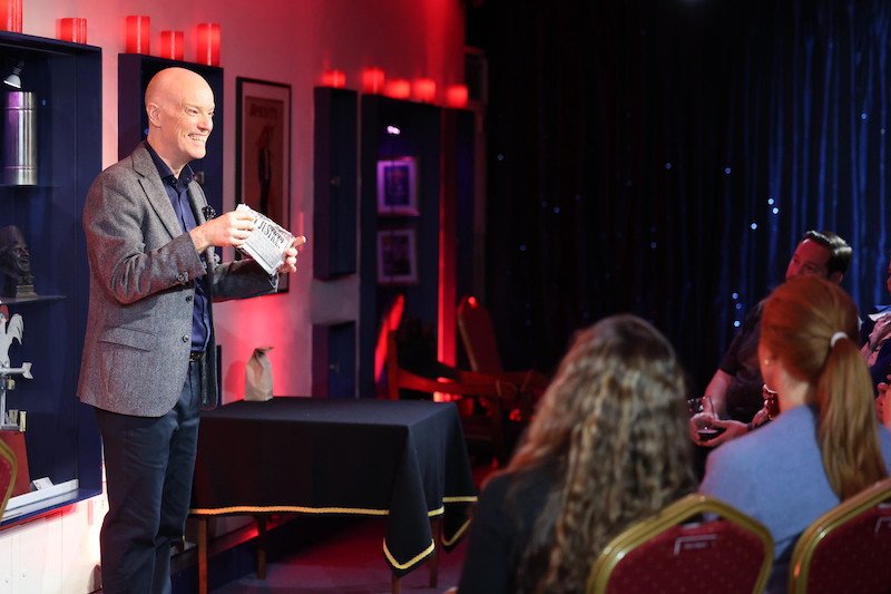 Darren Delaney performing a torn and restored newspaper magic trick at The Magic Circle