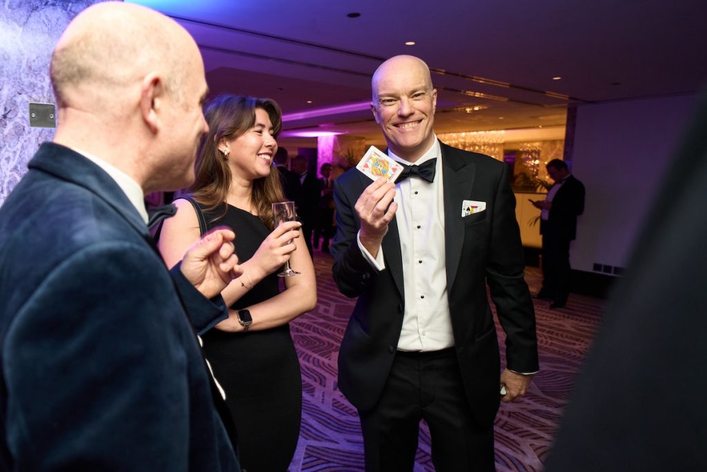 Darren Delaney performing a card trick while guests react at The Banking Tech Awards 2025