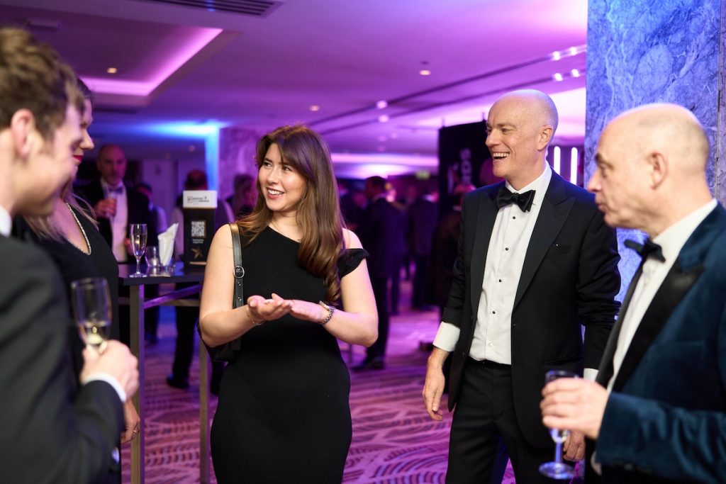Guests in formal wear and black tie reacting to Darren Delaney's close-up magic at The Banking Tech Awards 2025