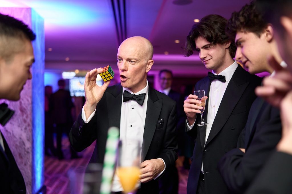 Magician Darren Delaney in black tie performing a magic trick with a Rubik's cube at The Banking Tech Awards 2025