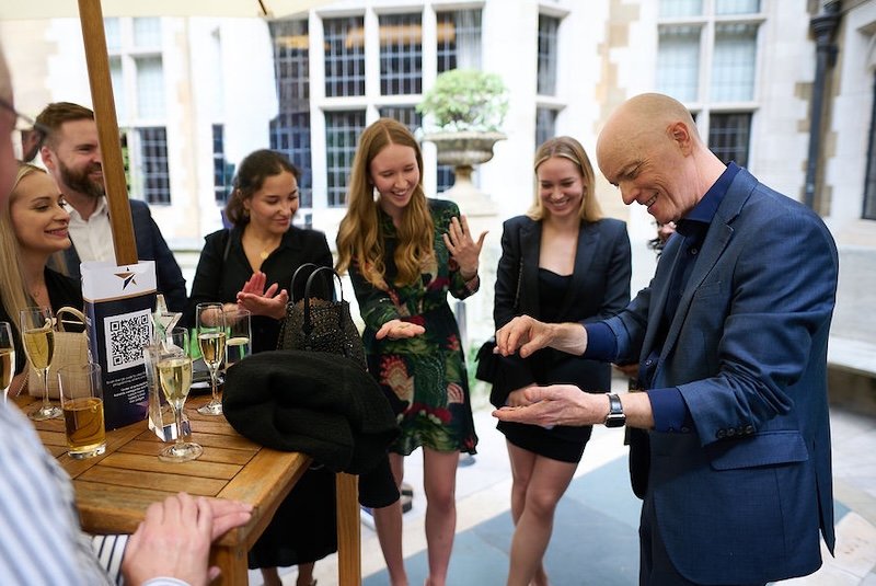 Darren Delaney performing magic for a group of people at a corporate drinks event