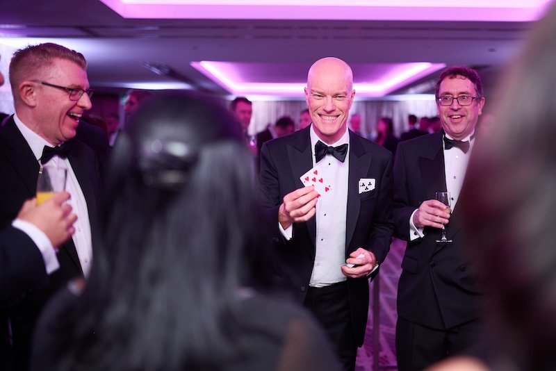 Corporate Event Magician Darren Delaney performing card tricks for a small group at a black tie event.